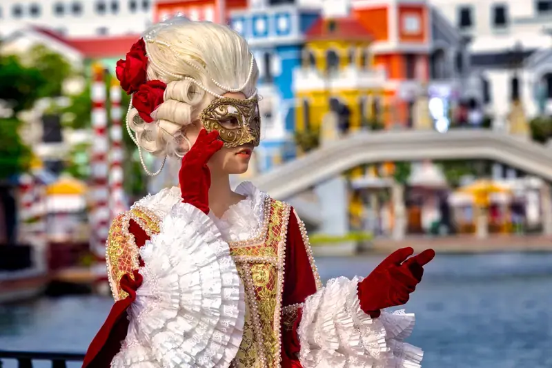 A masked performer in red and white costume beside the Grand World canal