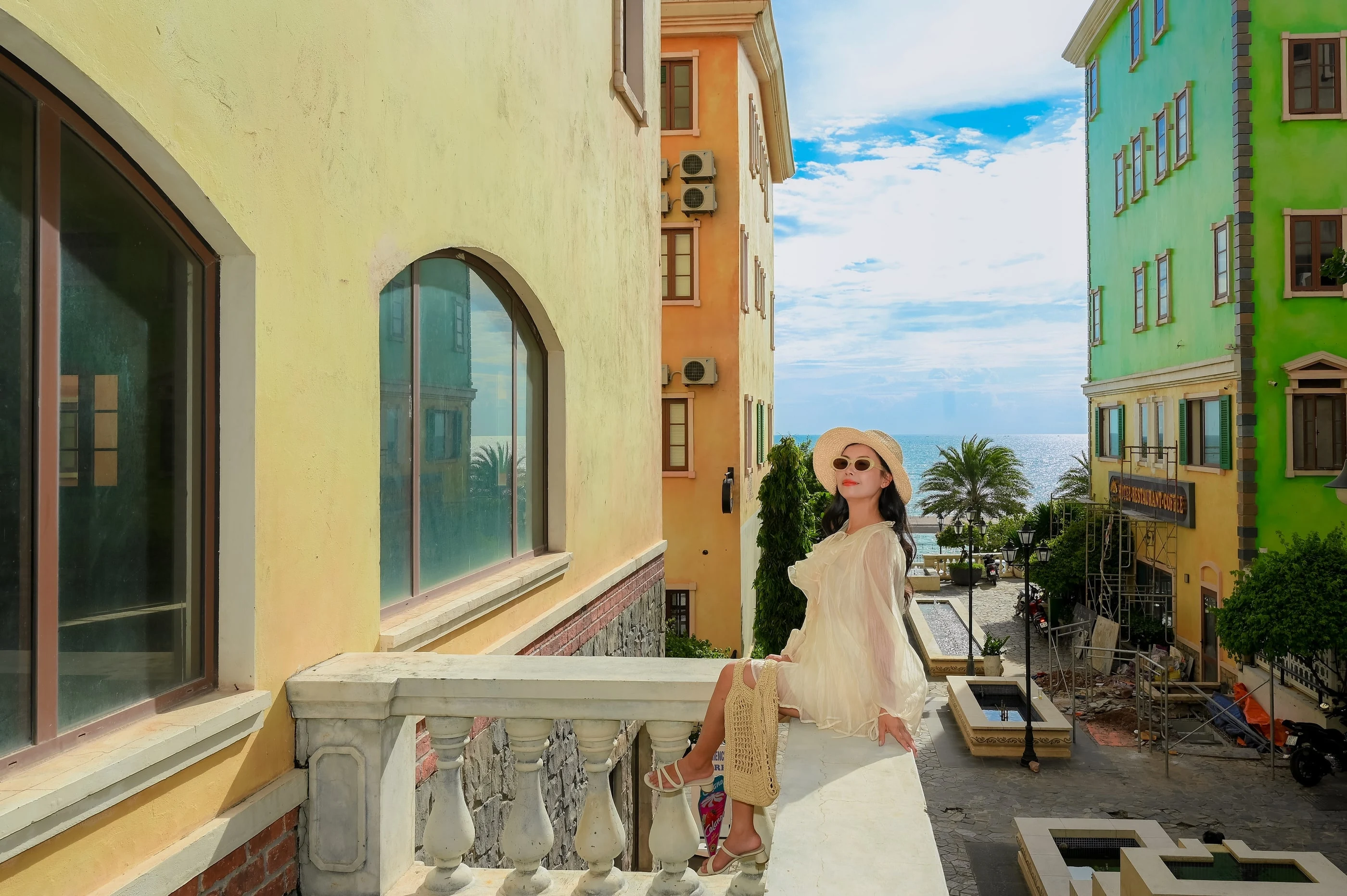 Người phụ nữ đội nón chụp chân dung giữa các tòa nhà nhiều màu tại Sunset Town Phú Quốc