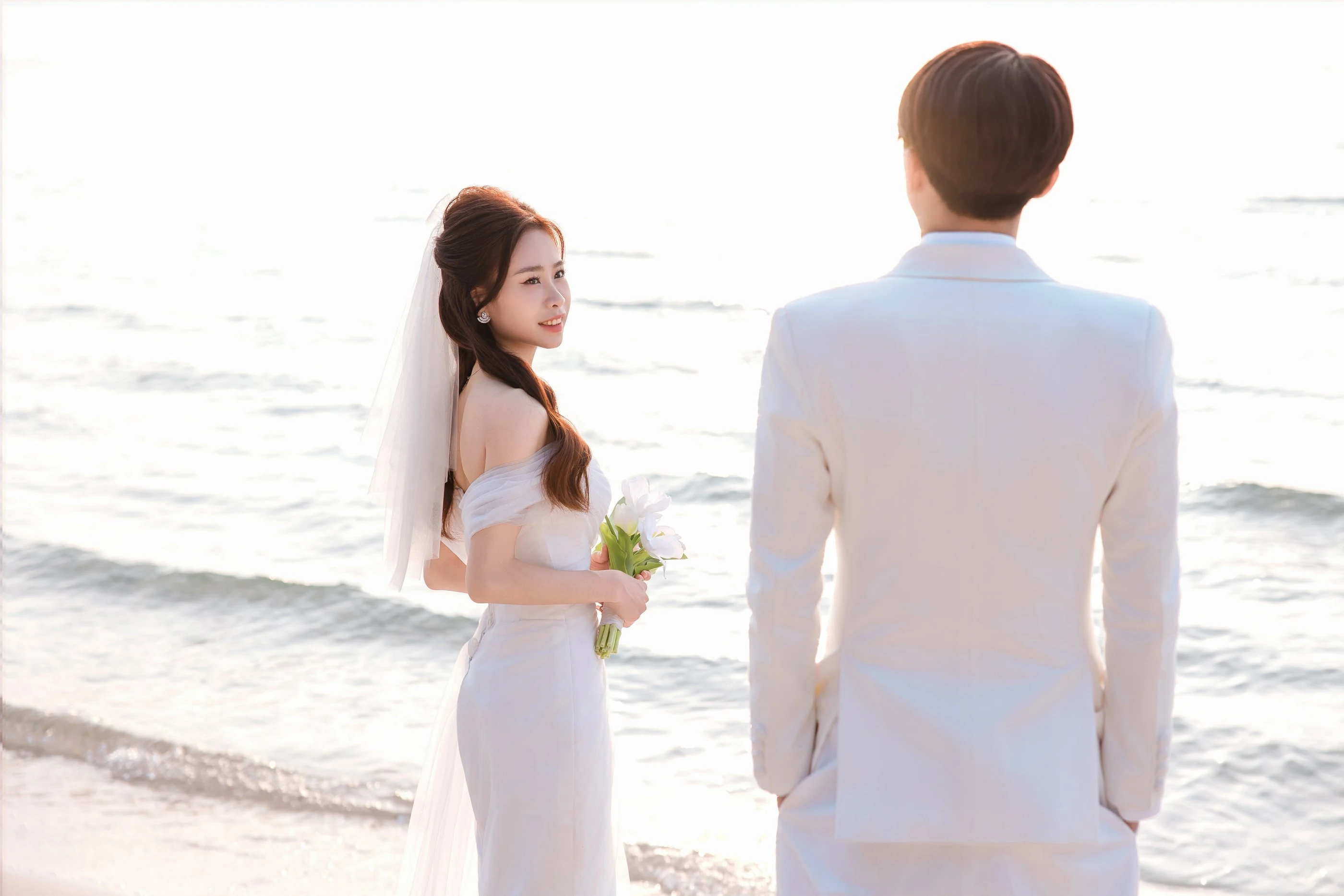 Cô dâu cầm hoa nhìn chú rể trong buổi chụp ảnh pre-wedding bên biển Phú Quốc