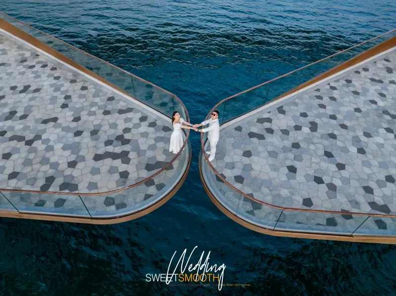Overhead view of a couple holding hands between the curved ends of Kiss Bridge, with a Wedding Sweet Smooth graphic below.